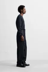 Pantalón de vestir negro de corte recto, con cintura elástica, pliegues frontales, bolsillos laterales y traseros.