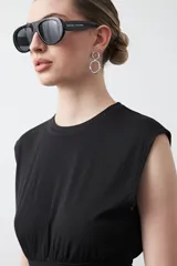 Top sin mangas color beige, confeccionado en tejido acanalado. Presenta hombreras definidas y un recorte fruncido bajo el busto que ajusta la silueta.