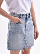 Minifalda blanca de denim con corte evasé y ruedo desflecado.