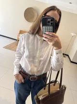 Camisa blanca de lino con cuello mao y detalle de puntilla de algodón en cuello y cartera de botones. Cierre frontal con botones de nácar.