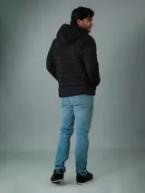 Campera acolchada negra con capucha, cierre frontal con cremallera y bolsillos laterales con cremallera. Logo de Calvin Klein en el pecho.