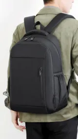 Mochila negra con bolsillos frontales verticales y laterales de rejilla. Tiene compartimento para notebook y faja trasera para sujetarla a la valija.