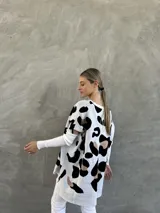Sweater de punto con estampado animal print en tonos blanco, negro y marrón. Diseño oversize con mangas 3/4 y aberturas en los hombros.