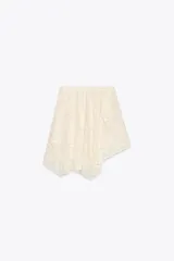 Falda corta de encaje color crema con forro interior. Presenta cintura elástica y bajo asimétrico con terminación en picos.