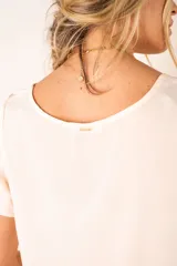 Blusa color crudo de poliéster con mangas cortas y cuello redondo.