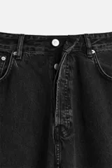 Pantalón de jean negro de corte amplio, con cinco bolsillos, efecto lavado y cierre frontal con cremallera y botón.