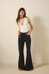 Pantalón de jean azul oscuro, de tiro medio y calce ajustado. Pierna acampanada desde la rodilla.