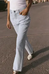 Pantalón de tiro alto con cinco bolsillos, estampado a rayas verticales celestes y blancas, de pierna recta y tejido con hilo metalizado.