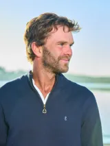 Sweater azul marino de punto, con cuello alto y medio cierre con cremallera. Tiene mangas largas y logo bordado en el pecho. Corte clásico.