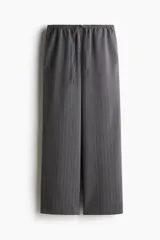 Pantalón gris oscuro a rayas verticales finas, de corte holgado, con elástico y cordón ajustable en la cintura, bolsillos laterales y bolsillos decorativos en la parte trasera. Confeccionado en sarga.