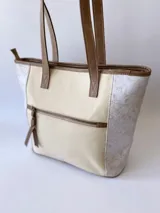 Bolso tipo tote bag color beige con laterales estampados y detalles en cuero marrón.