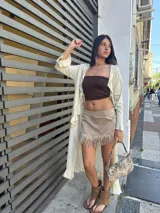 Maxi camisa color crema, con cuello en V, mangas largas con volados y cinturón marrón con tachas.