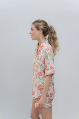 Conjunto de pijama de algodón a rayas verticales rosas y blancas, con detalles en celeste. Incluye camisa de manga corta con botones y bolsillo en el pecho, y shorts con cintura elástica.