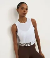 Musculosa deportiva corta (crop top) blanca, con cuello redondo y sisas amplias. Presenta un panel frontal de tela transparente/mesh sobre el busto y la palabra "SPORTY" estampada en color marrón en el bajo.