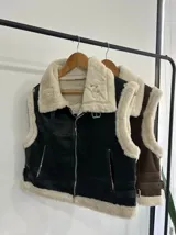 Chaleco marrón con cuello de piel sintética color crema, cierre frontal con cremallera y bolsillos laterales.