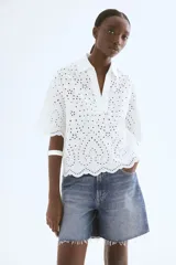 Camisa blanca de algodón con broderie, corte holgado, cuello abierto, mangas anchas al codo y ribete festoneado en mangas y bajo.
