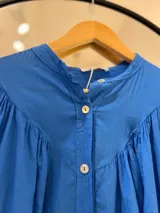Camisa azul francia de manga larga con puño, cuello mao y cierre frontal con botones.