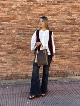 Bolso matero de cuero color chocolate con textura croco, asas cortas y detalle de costuras en los laterales. Incluye un dije con flecos en tonos beige y negro.