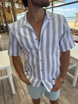 Camisa de manga corta con rayas verticales grises y blancas, cuello americano y botones marrones.