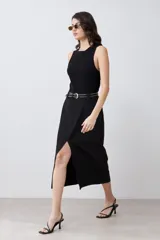 Falda midi negra de corte recto, con tajo lateral y cinturón con hebilla metálica.