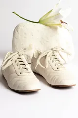 Zapatillas acordonadas color beige con detalles en blanco.