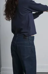 Pantalón de jean azul oscuro, corte amplio, tiro alto y bota ancha.