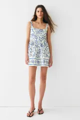 Vestido corto de algodón con estampado de motivos marinos en azul, con costuras estilo corset adelante y atrás. Modelo de cuerpo entallado con breteles anchos, escote cuadrado y cierre oculto con corchete en la espalda. Costura fruncida en la cintura y pollera con vuelo. Cuerpo forrado.