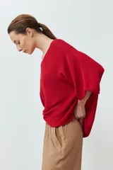 Sweater de punto color rojo, con diseño oversized, escote en V y mangas anchas de estilo murciélago.