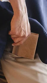 Billetera de cuero color marrón claro con guarda inferior combinada. Tiene dos visores, doble repartición para billetes, tarjeteros y bolsillos.