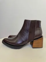Botines de cuero color marrón con textura de piel de cocodrilo, paneles laterales elásticos de gamuza, puntera cuadrada y tacón geométrico de madera.