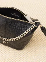 Bandolera negra de cuero vacuno con correa regulable y cadena metálica ornamental. Interior forrado en cuero vacuno con bolsillo interno con cierre.