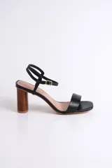Sandalias negras de cuero con tacón cilíndrico de madera y tira fina en el tobillo.