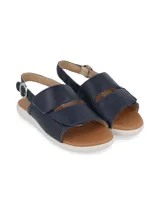 Sandalia azul marino de cuero con ajuste de velcro y suela blanca.