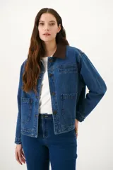 Chaqueta de jean azul con cuello de pana color camel, corte recto y bolsillos frontales.