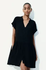 Vestido corto negro de tejido arrugado con cuello mao y abertura en V, mangas cortas con doblez, botones forrados y costura fruncida en la cadera.