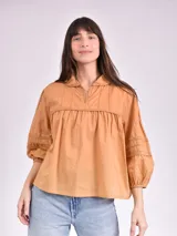 Blusa color beige con cuello mao, escote en V y mangas 3/4 con elástico en los puños.