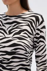 Sweater de tejido de punto, color crema, con estampado floral en tonos rosados y marrones. Presenta cuello redondo y mangas largas.