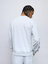 Buzo gris melange de felpa sin frisa, con cuello redondo y logo de Umbro bordado en azul marino en el pecho.