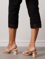 Pantalón capri negro de algodón con terminación de ruedo con aplique calado.