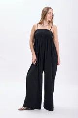 Mono largo negro con breteles finos y corte palazzo. Incluye cinturón ancho de cuero sintético con hebilla metálica y tachas.