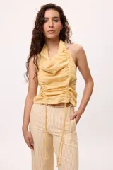 Top blanco sin mangas con cuello halter y frunces ajustables en el frente. Confeccionado en algodón y lino.