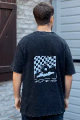 Remera negra de algodón con estampa en la espalda de un cartón de jugo con carita sonriente sobre un fondo a cuadros y la frase "Good Vibes Juice".