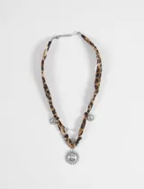 Collar con cinta de tela estampada animal print (leopardo) que funciona como gargantilla. Incluye un dije central grande con forma de sol plateado, dos dijes pequeños con forma de sol o estrella, y una perla blanca colgando.