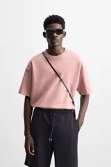 Camiseta rosa de corte recto, cuello redondo y manga corta. Estampado con efecto grabado combinado a tono en la espalda.