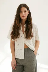 Camisa blanca con estampado de lunares negros, de corte clásico, manga corta y cuello camisero.