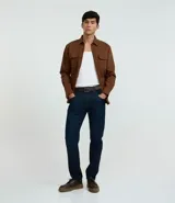 Pantalón slim fit confeccionado en tejido denim azul oscuro, con cintura con trabillas, cierre tradicional y bolsillos.