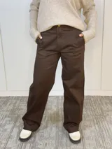 Pantalón marrón de tiro alto, corte ancho y botón dorado.