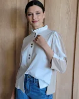 Camisa de manga larga color blanco y beige, con cuello con volados y cierre frontal con botones.
