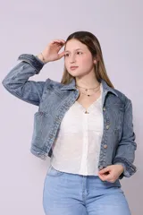 Campera de jean de color azul oscuro, con corte cropped y costuras en contraste color caramelo. Presenta cuello clásico, cierre frontal con botones metálicos y bolsillos a la altura del pecho y laterales.