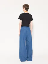 Pantalón de cintura alta confeccionado en denim camisero liviano, color celeste. Presenta piernas amplias con tablas frontales, bolsillos laterales y ojales sastres en la espalda.